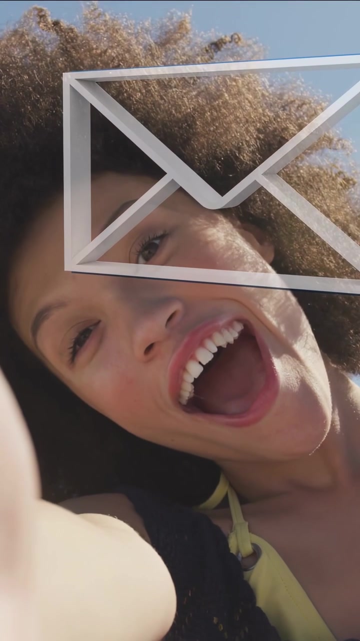 Donna che tiene il telefono in spiaggia, avvia una busta che si sovrappone al viso mentre manda un bacio per marketing