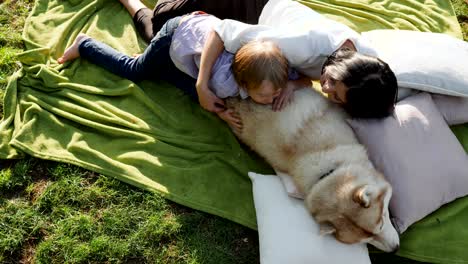 mom with son embrace dog and lie on green grass in park on background of nature