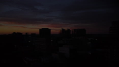 panorama del horizonte de la ciudad desde el sol amarillo brillante al atardecer hasta la oscuridad, el dron gira 180 grados