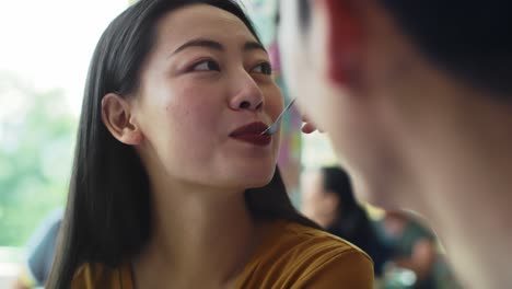 handheld view of man feeding woman dessert on a date