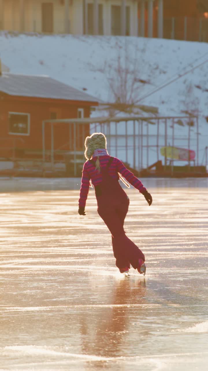 Elegantti hahmo liukuu jäätyneellä järvellä auringonlaskun aikaan, pukeutuneena violettiin asuun, vangiten luistelun seesteisen kauneuden rauhallisessa ulkoilmassa pehmeän kultaisen valon ympäröimänä.