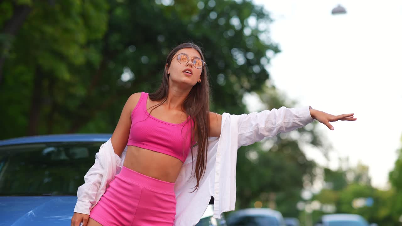 mujer con traje rosa en un coche azul