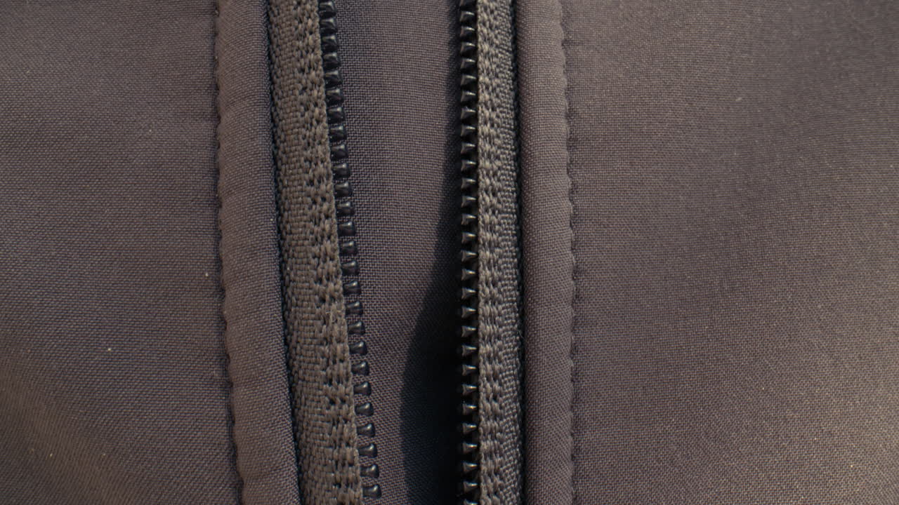 Close up of a hand unzipping a zipper