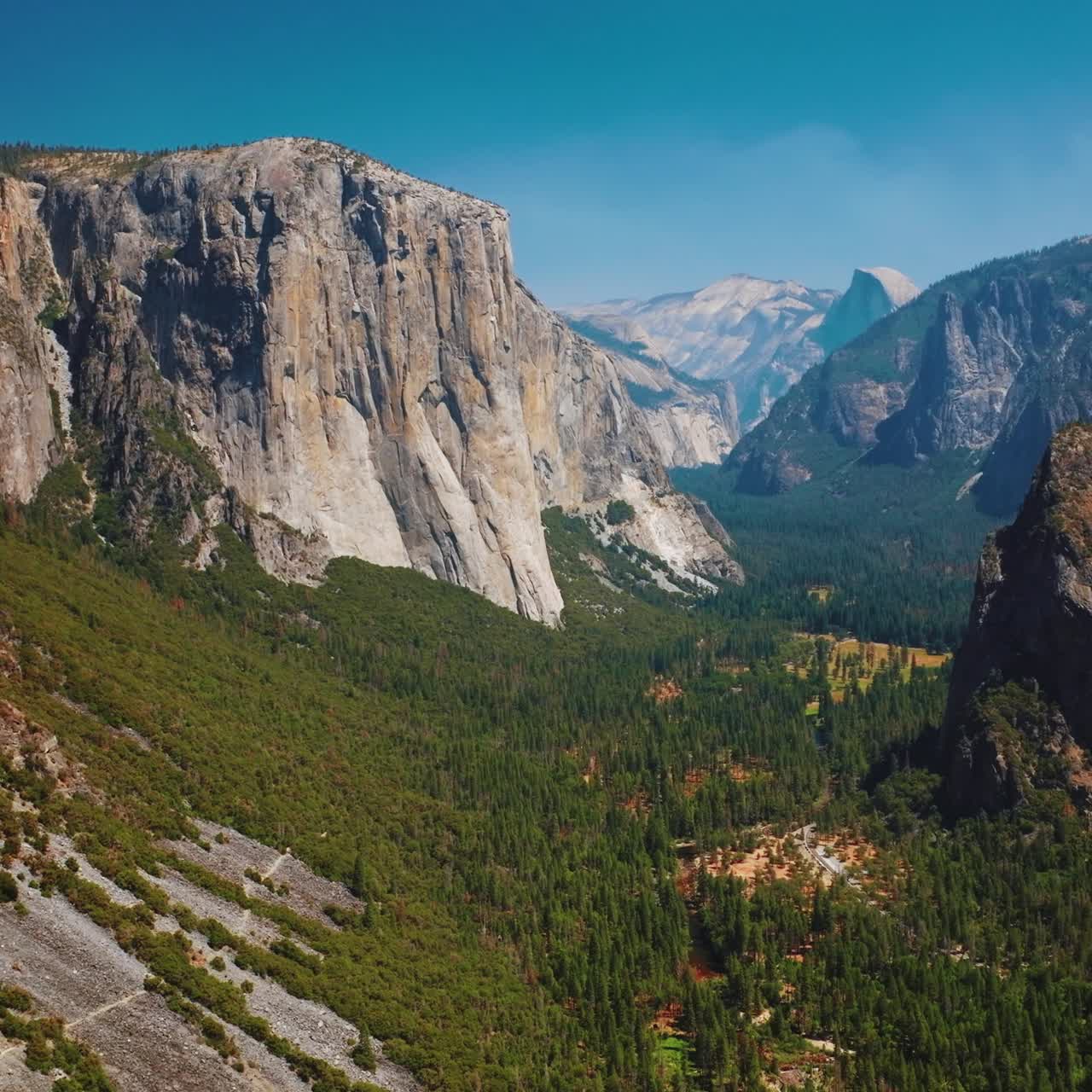 Bright sunny day scenery in Yosemite National Park, California, USA. Amazing cliff mountains with green forests at its foot. Aerial view