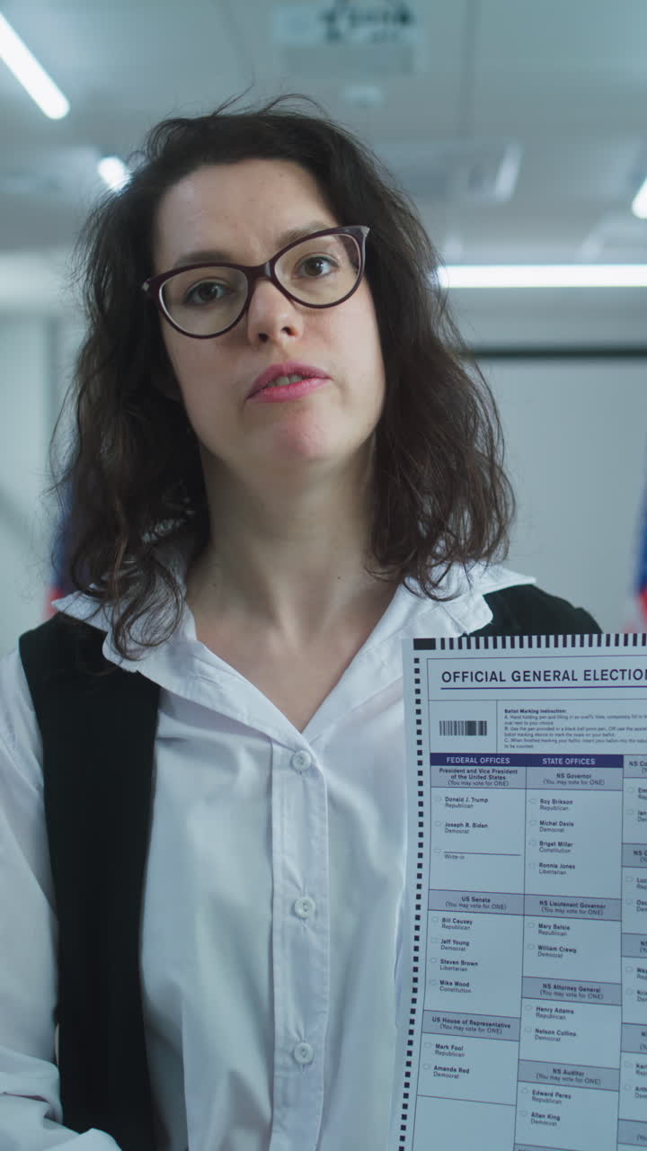 American Woman Speaks on Camera Shows Paper Bulletin Calls for Voting American Woman Speaks on Camera Shows Paper Bulletin Calls for Voting National Elections Day in the United States Voting Booths at Polling Station Concept of Civic Duty and Patriotism Portrait