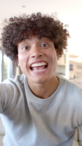 vertical video: yawning, young man with curly hair relaxing during friends hangout indoors