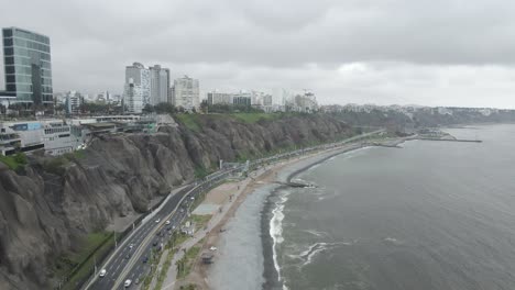 Highway-traffic-below-steep-eroding-Pacific-cliffs-of-Miraflores,-Peru