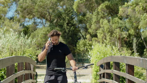 Long-shot-of-biker-with-bionic-leg-talking-on-phone-in-park