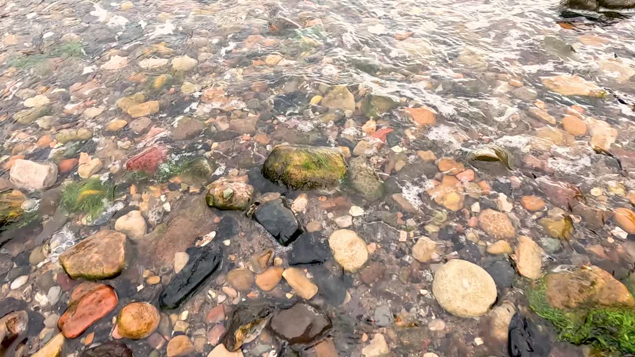 Onde accarezzano delicatamente ciottoli colorati sulla spiaggia