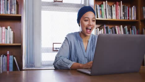 Asiatische-Studentin-Trägt-Einen-Blauen-Hijab,-Sitzt-Mit-Laptop-Und-Jubelt