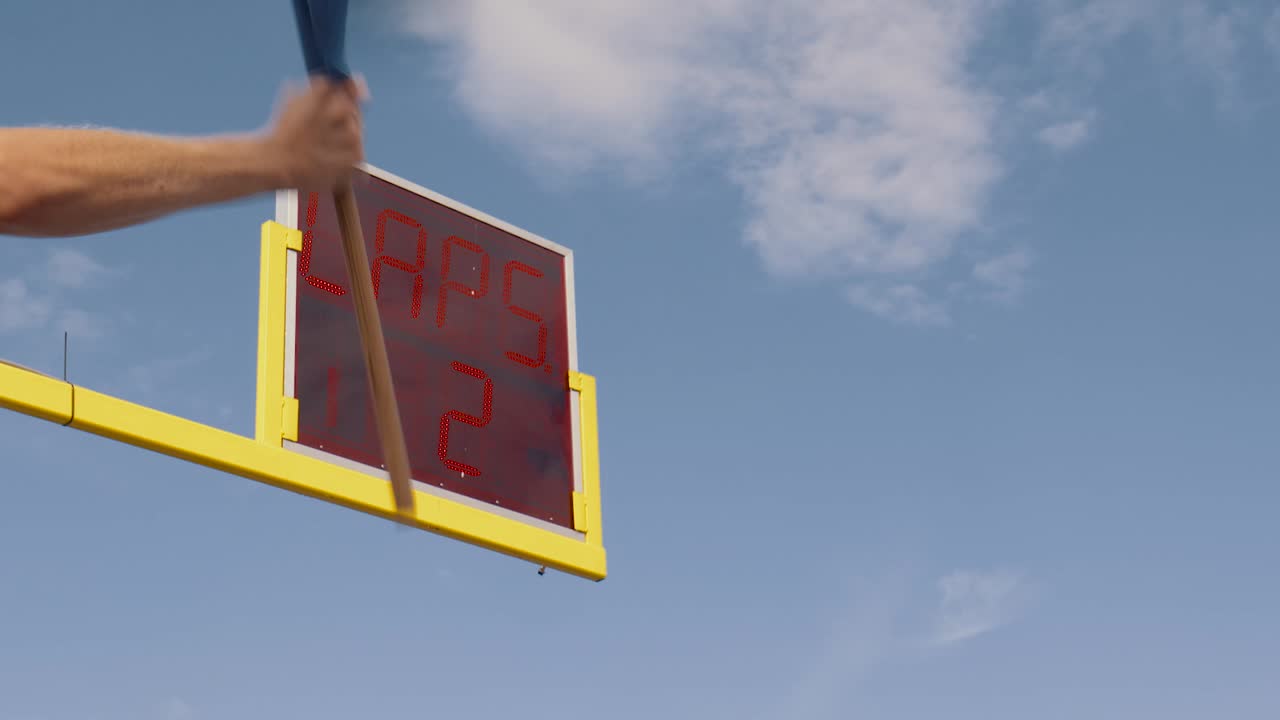 ondeando la bandera azul frente al contador de vueltas, la vuelta 3 cambia a la vuelta 2