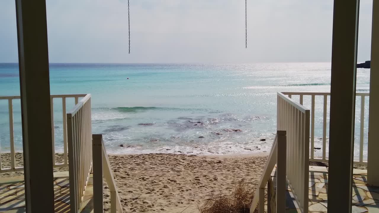 Blue waves of the Mediterranean sea flowing to the sandy coast, view from inside the house