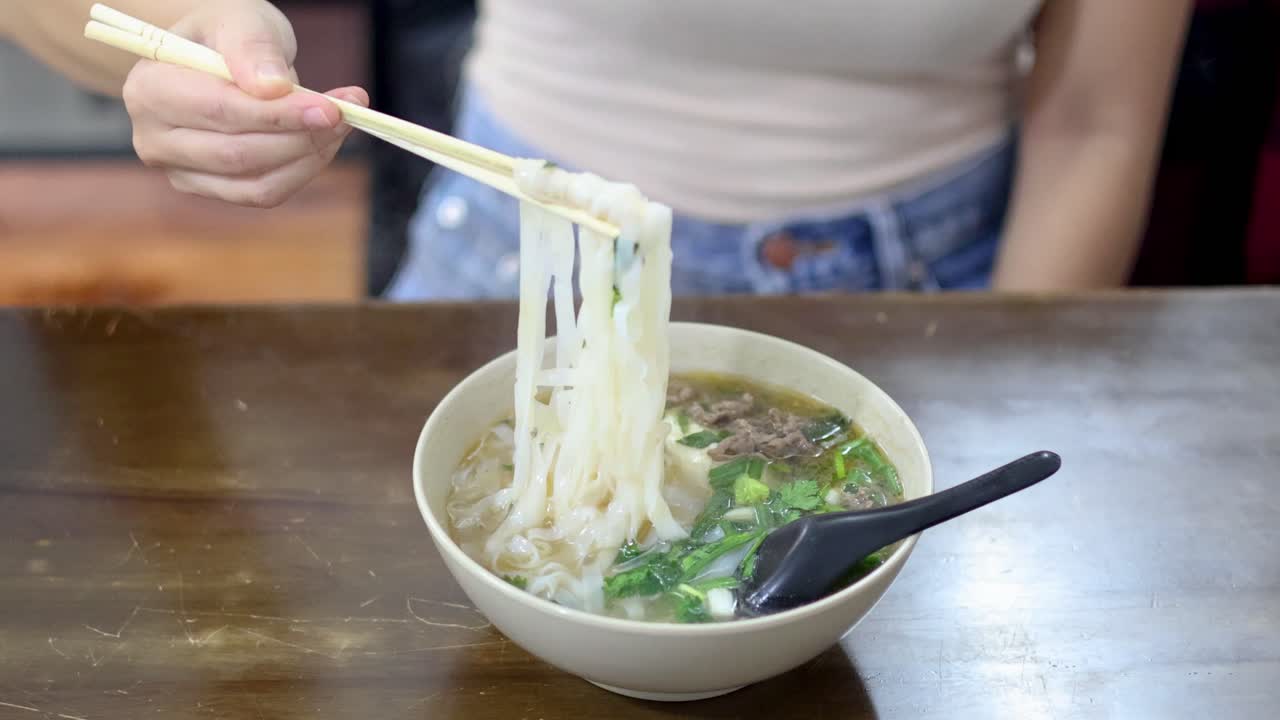 Person enjoying a bowl of Vietnamese pho