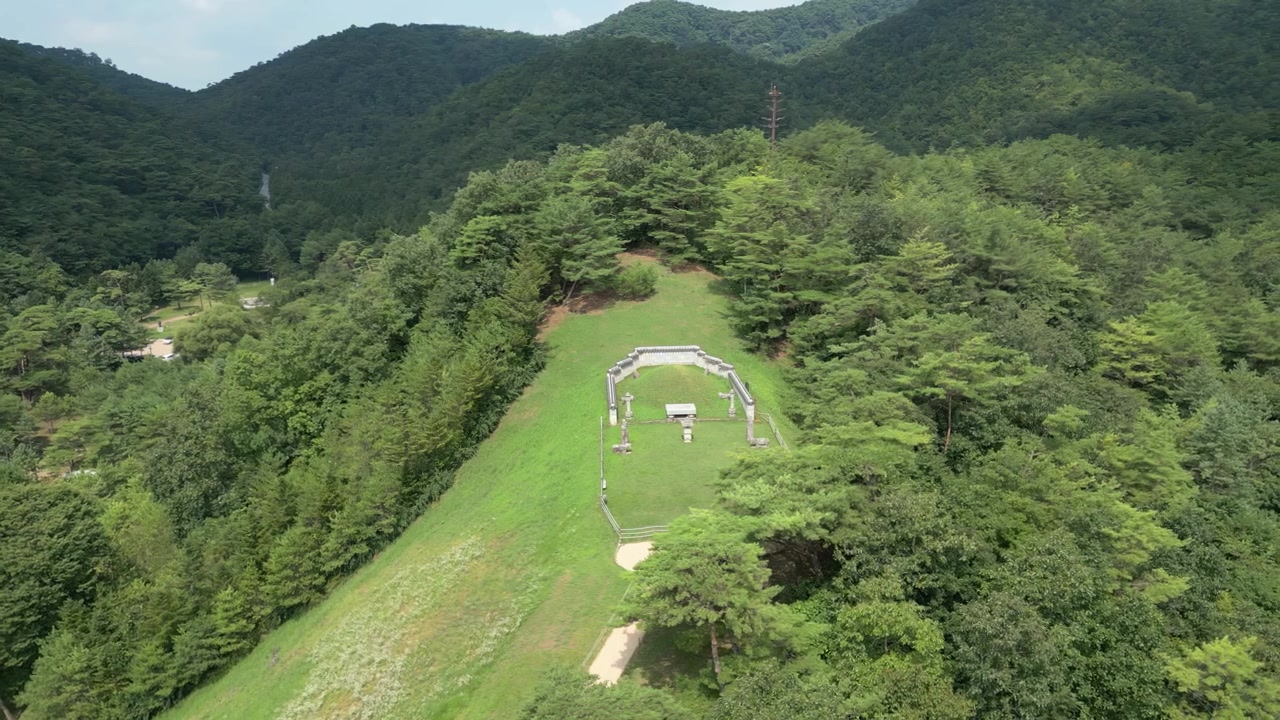 豊かな森林と山々の景色に囲まれた古代韓国の王陵をドローンが滑らかに空撮旋回