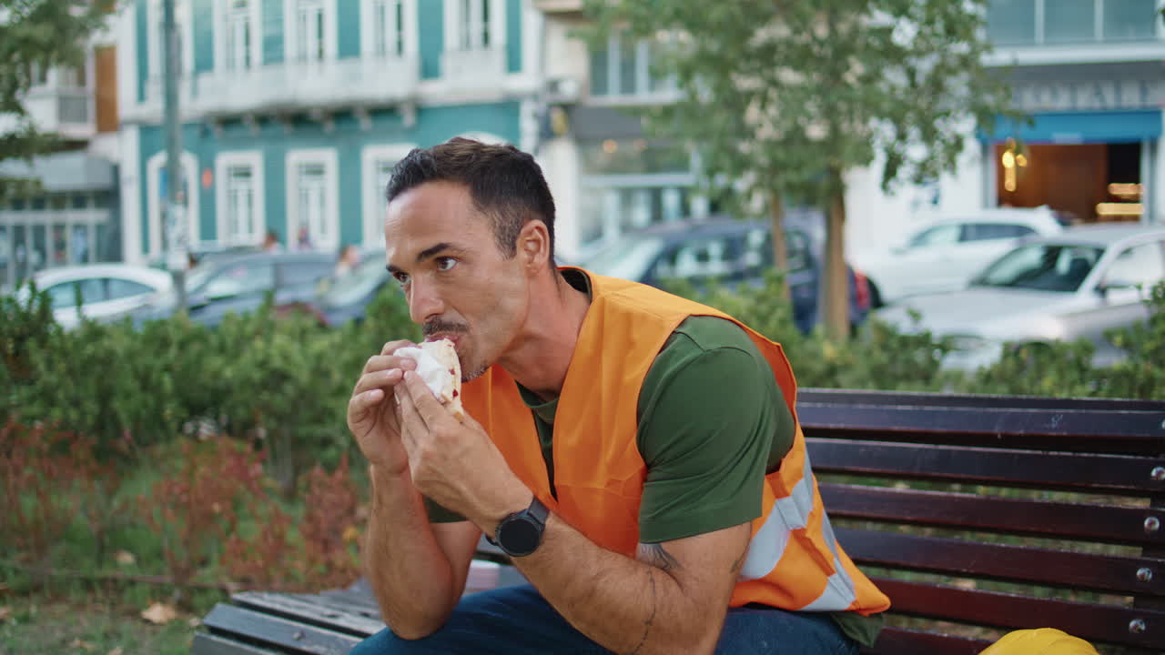 Relaxed builder resting break eating lunch street closeup. Man tasting sandwich