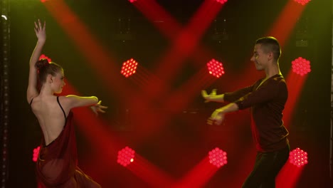 elegant dance performance by a couple under red and yellow stage lights