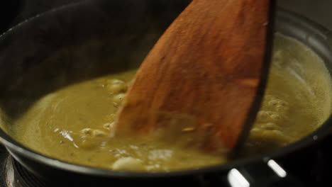 green boiling sauce texture close-up macro. cooking green curry with wooden spoon at home.