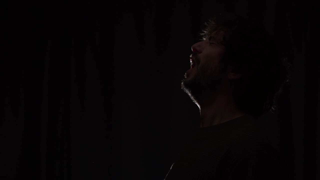 Slow-motion of a man sneezing and releasing droplets into the air