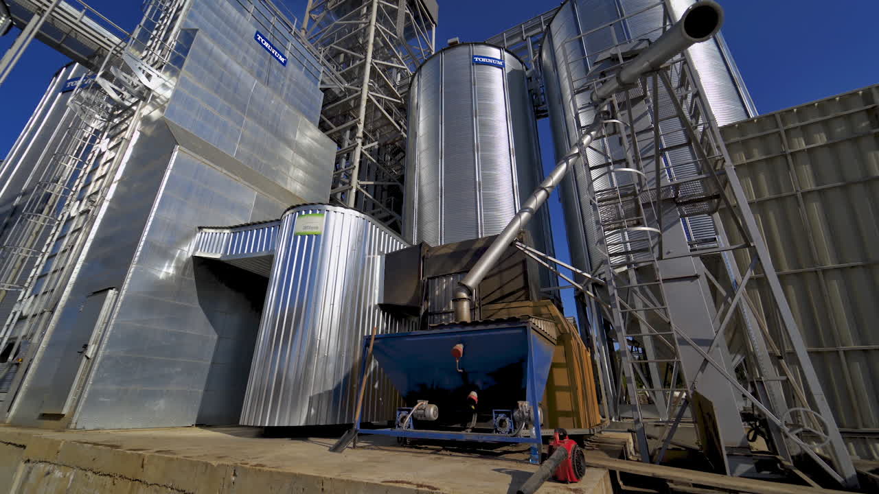 Exterior of industrial plant. Modern construction of grain elevators outdoors. Metal granary for storing crop. Industrial equipment outdoors.