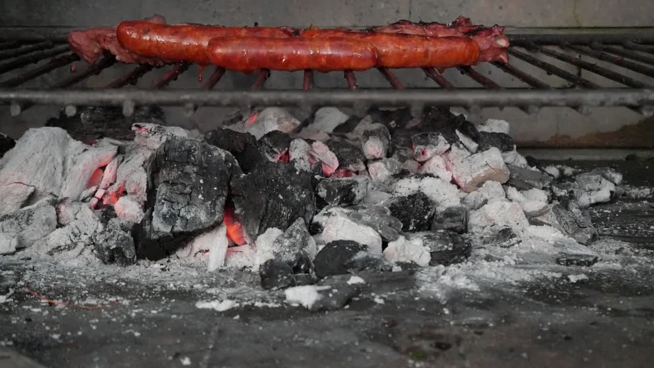 Grilled sausages cooking over glowing charcoal in a rustic BBQ setting