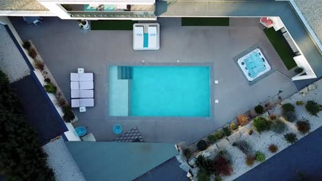 top down shot of a drone ascending to the terrace of a residential house with a deflated swimming pool and sun loungers spread around it