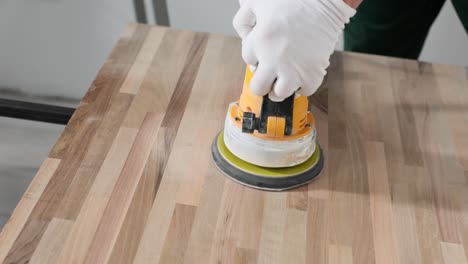 sanding a wooden surface with an orbital sander