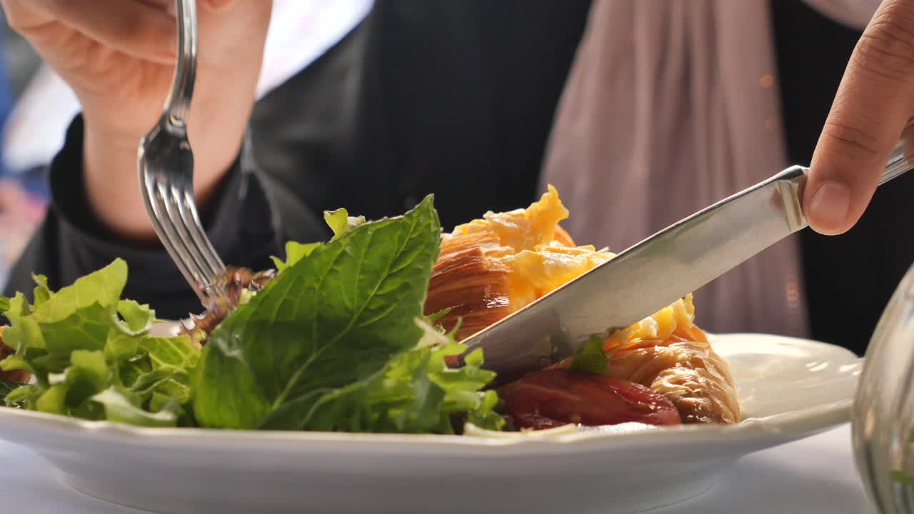 Close-up of a Person Enjoying a Croissant and Scrambled Eggs Breakfast