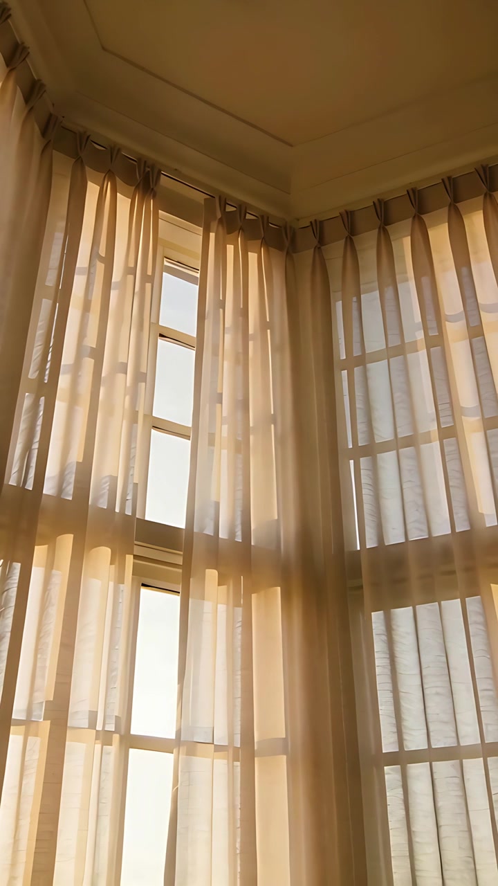 Video vertical: Cámara inclinándose hacia arriba mientras el cálido sol brilla a través de una rejilla en un pasillo, mostrando cortinas transparentes del techo.