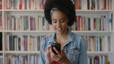 portrait happy young african american girl using smartphone enjoying browsing online texting sending sms messages smiling happy black woman in library bookstore