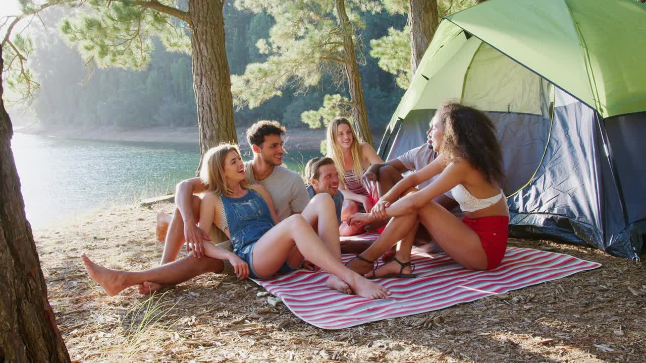 Amici che si rilassano su una coperta da picnic in riva a un lago