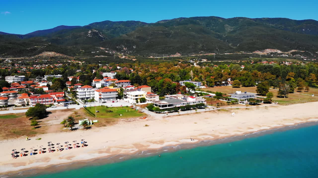 View of Asprovalta from the drone. Buildings and greenery, long beach along the town. Blue water of the Aegean sea. Green hills on the background. Greece