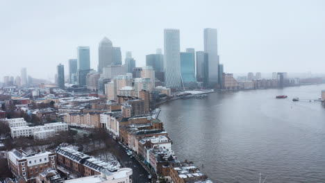 Kreisende-Drohnenaufnahme-Von-Canary-Wharf-Wolkenkratzern-Im-Schnee-Von-Limehouse