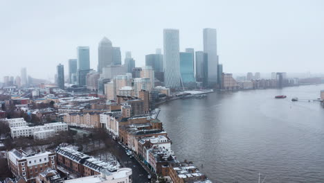 circling drone shot of canary wharf skyscrapers in the snow from limehouse