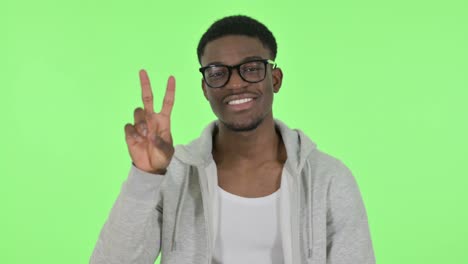 african man showing victory sign on green background