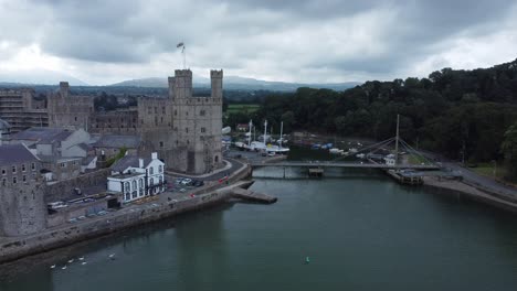 ancient caernarfon castle welsh harbour town aerial view medieval waterfront landmark slow forward shot