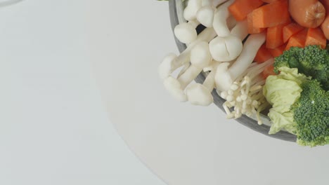 cerca de una olla de ingredientes de shabu girando alrededor de la mesa blanca en la cocina