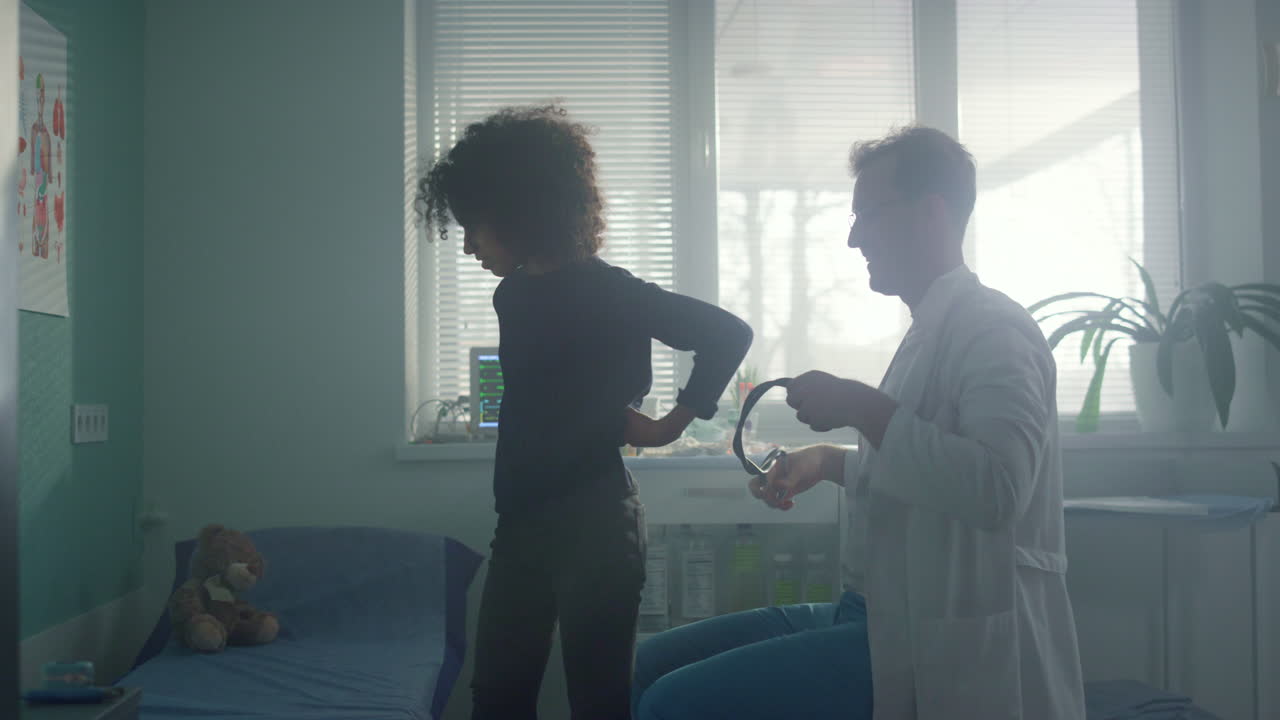 médico pediatra usando un estetoscopio escuchando los pulmones de una adolescente en una clínica moderna