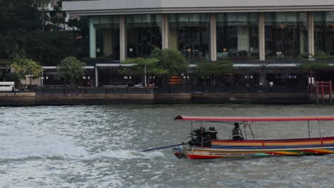 a longtail boat speeds along a river