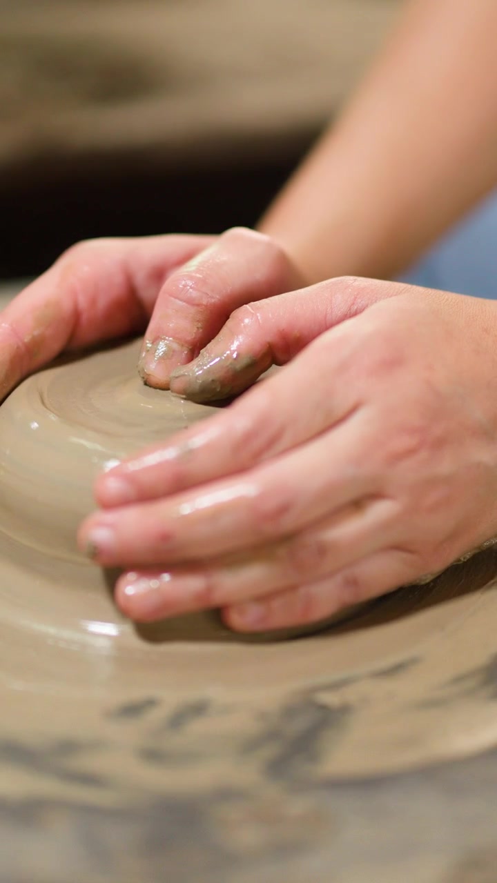 Primo piano dettagliato di mani che modellano argilla al tornio in un laboratorio di ceramica tradizionale in Thailandia