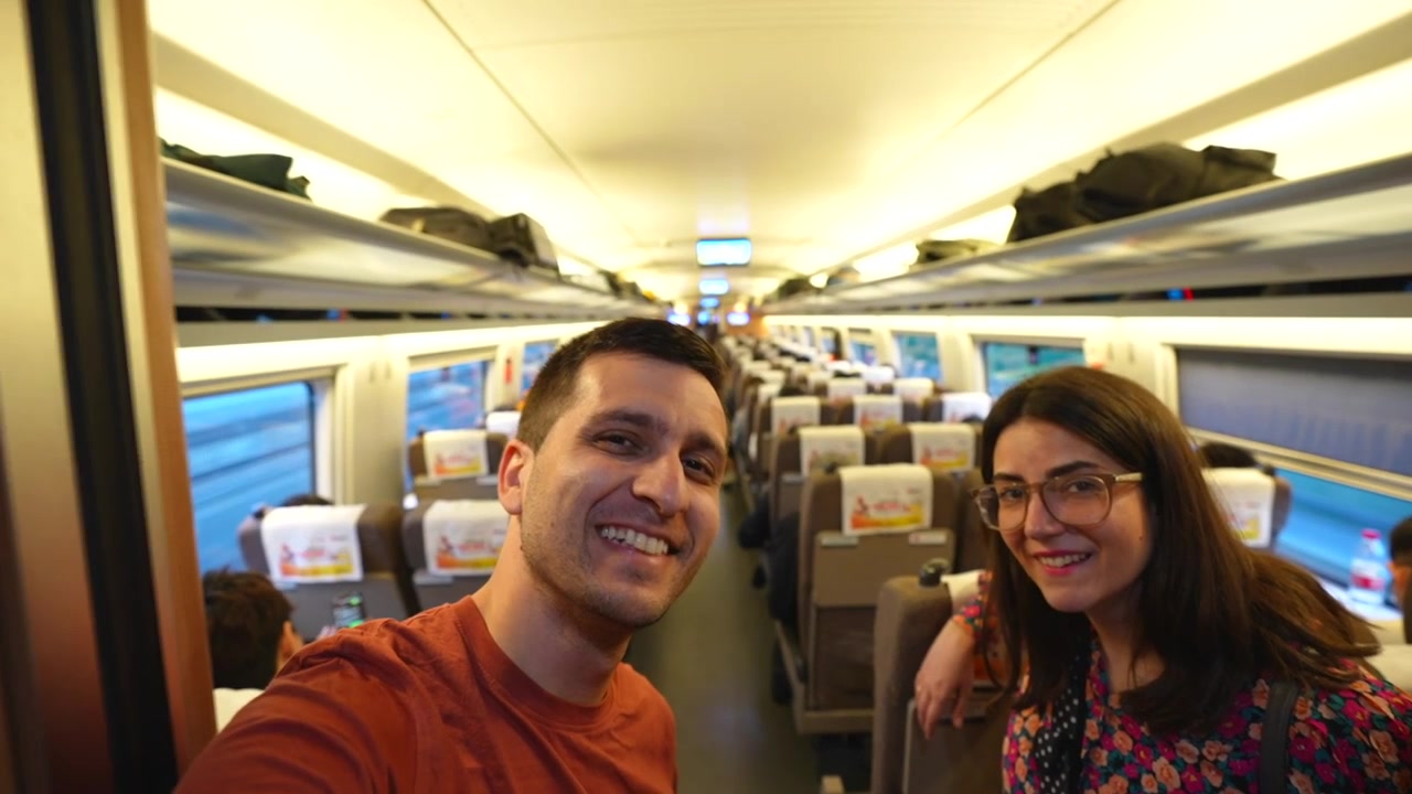 Pareja joven tomándose una selfie mientras viajan en un tren moderno de alta velocidad durante sus vacaciones en Asia.