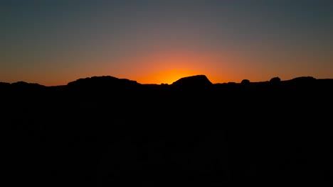 Langsamer-Schuss,-Der-über-Felsen-Aufsteigt-Und-Sonnenuntergang-Mit-Silhouetten-Von-Menschen-Am-Ufer-Am-San-Buenaventura-State-Beach-In-Ventura,-Kalifornien,-Vereinigte-Staaten-Enthüllt