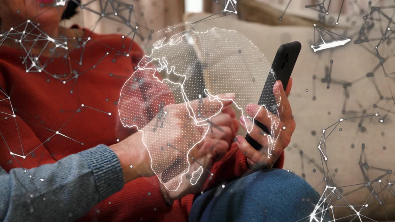 Senior couple leaning on sofa with man pointing initiating phone tapping and exploring tech globe