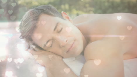 sleeping man resting on towel with heart shapes animation over background