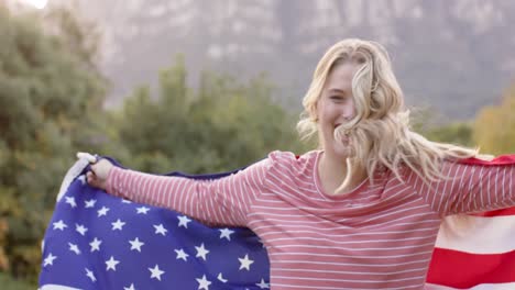 Portrait-of-caucasian-woman-holding-flag-of-usa-in-garden,-slow-motion