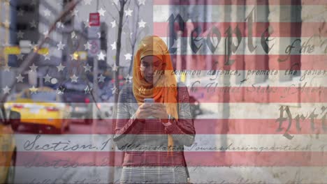 Animation-of-American-flag-waving-and-constitution-text-over-mixed-race-woman-in-hijab