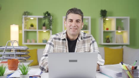 un trabajador feliz y sonriente que trabaja en la oficina de casa.