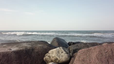 Pedestal-down-shot-of-rocks-in-front-of-wide-view-of-sea