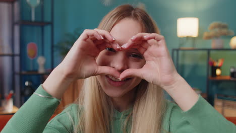 Happy-young-woman-girl-makes-symbol-of-love-showing-heart-sign-to-camera-express-romantic-feelings