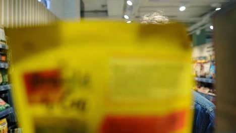 footage from the shelf. handsome man browses through shelf. picking pack from the shelf. slow motion