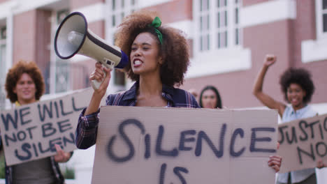 diverse group of men and women holding placards shouting using megaphone during protest